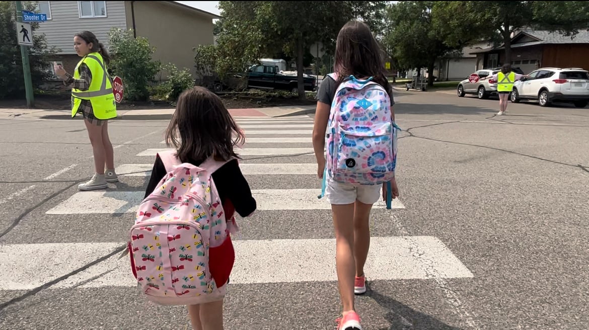 kids crossing street with a crosswalk patroller