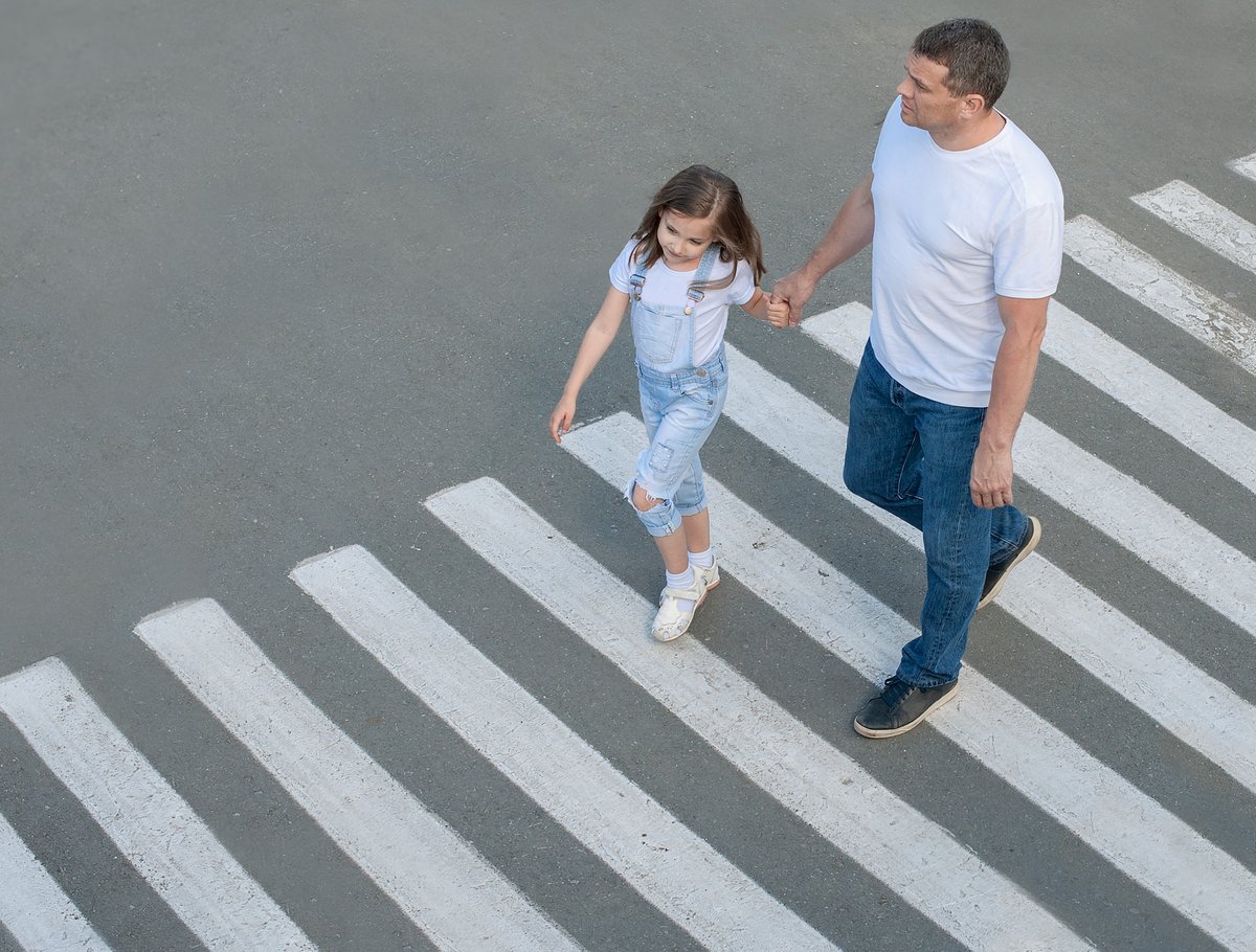 dad and daughter walking on a crosswalk